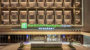 A hotel entrance with a modern facade, multiple balconies, and a sign indicating a Holiday Inn Express.