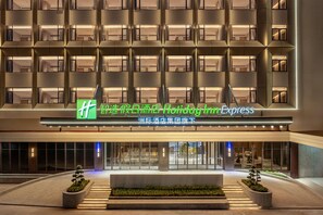 A hotel entrance with a modern facade, multiple balconies, and a sign indicating a Holiday Inn Express. - Holiday Inn Express Haikou World Trade Center (Haikou)
