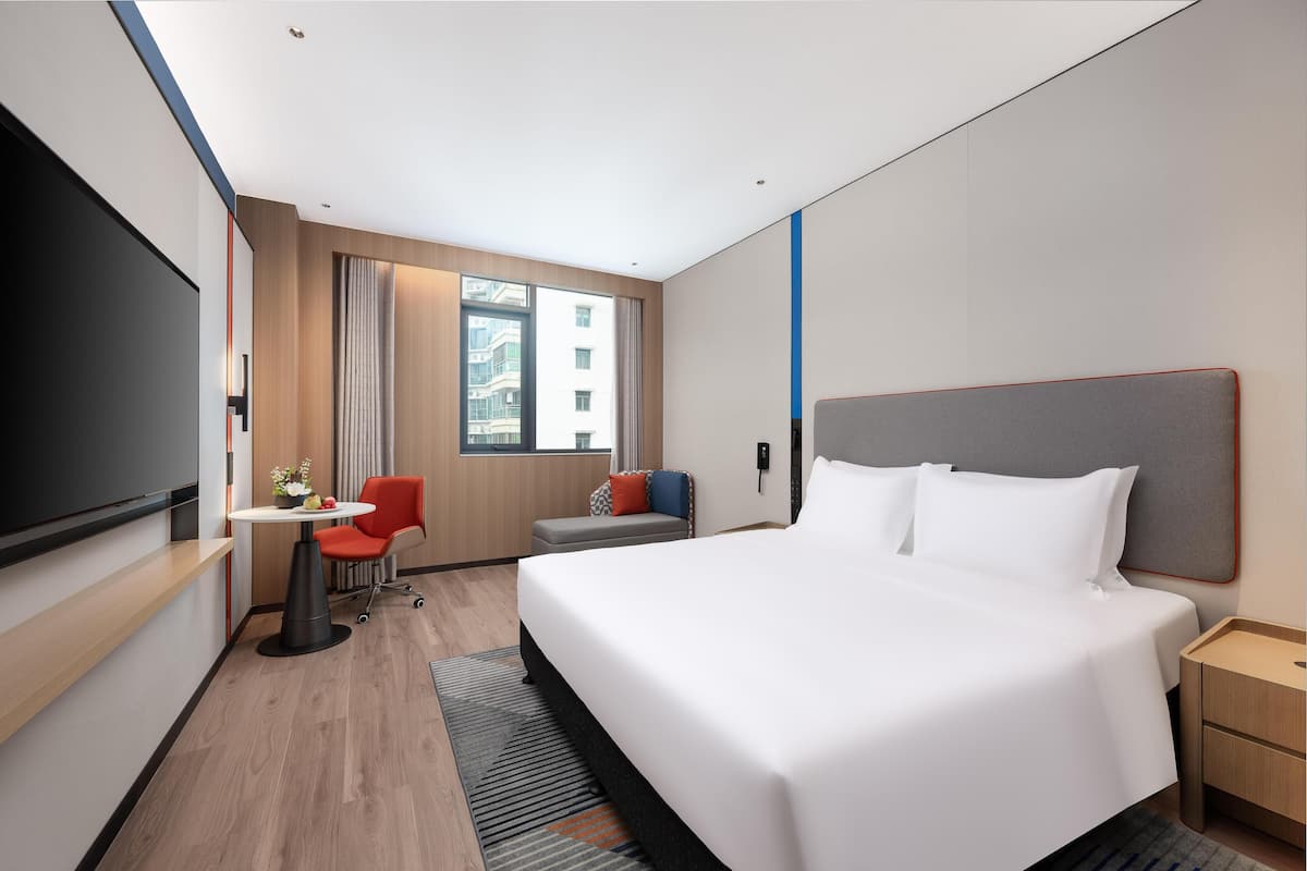 Habitación de hotel moderna con una cama grande, un escritorio, una silla y un televisor.