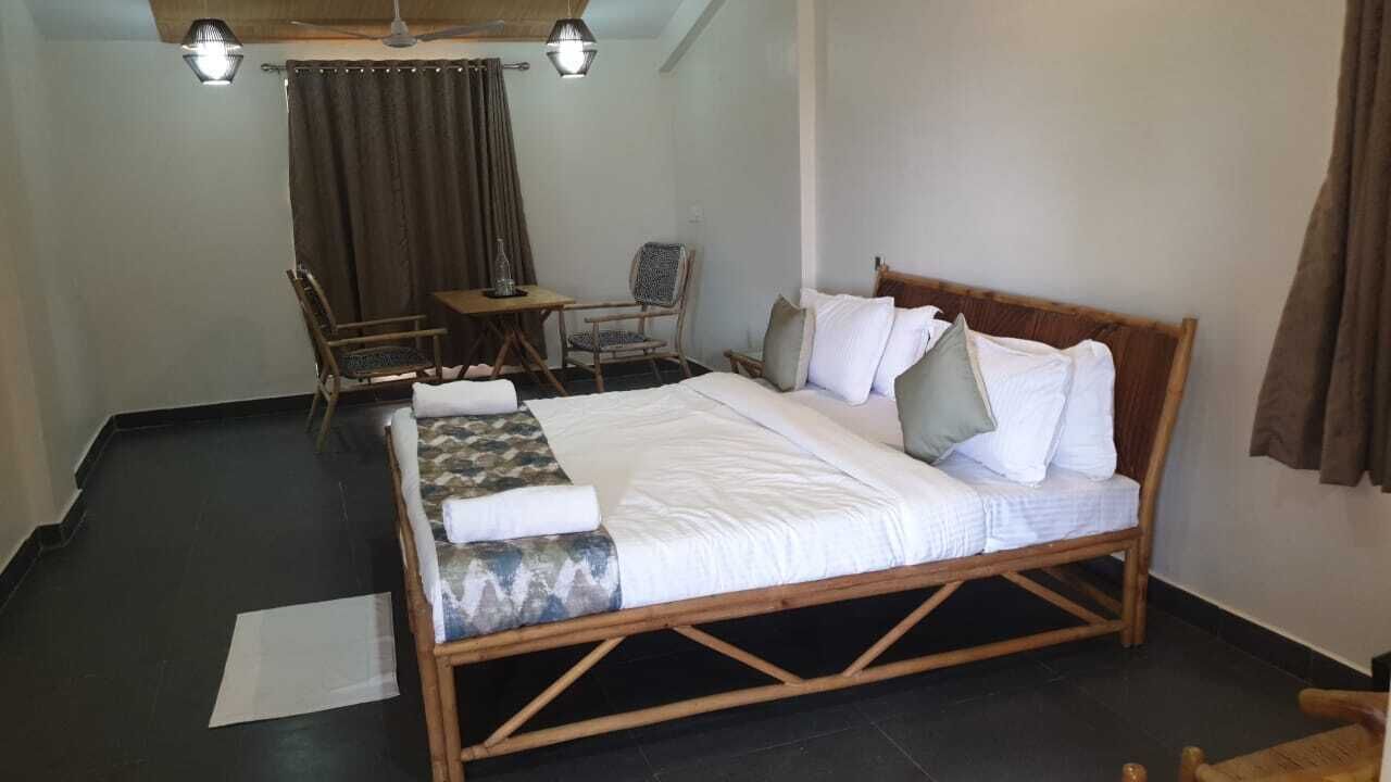 A bedroom with a wooden bed, two chairs, a small table, and a ceiling fan.