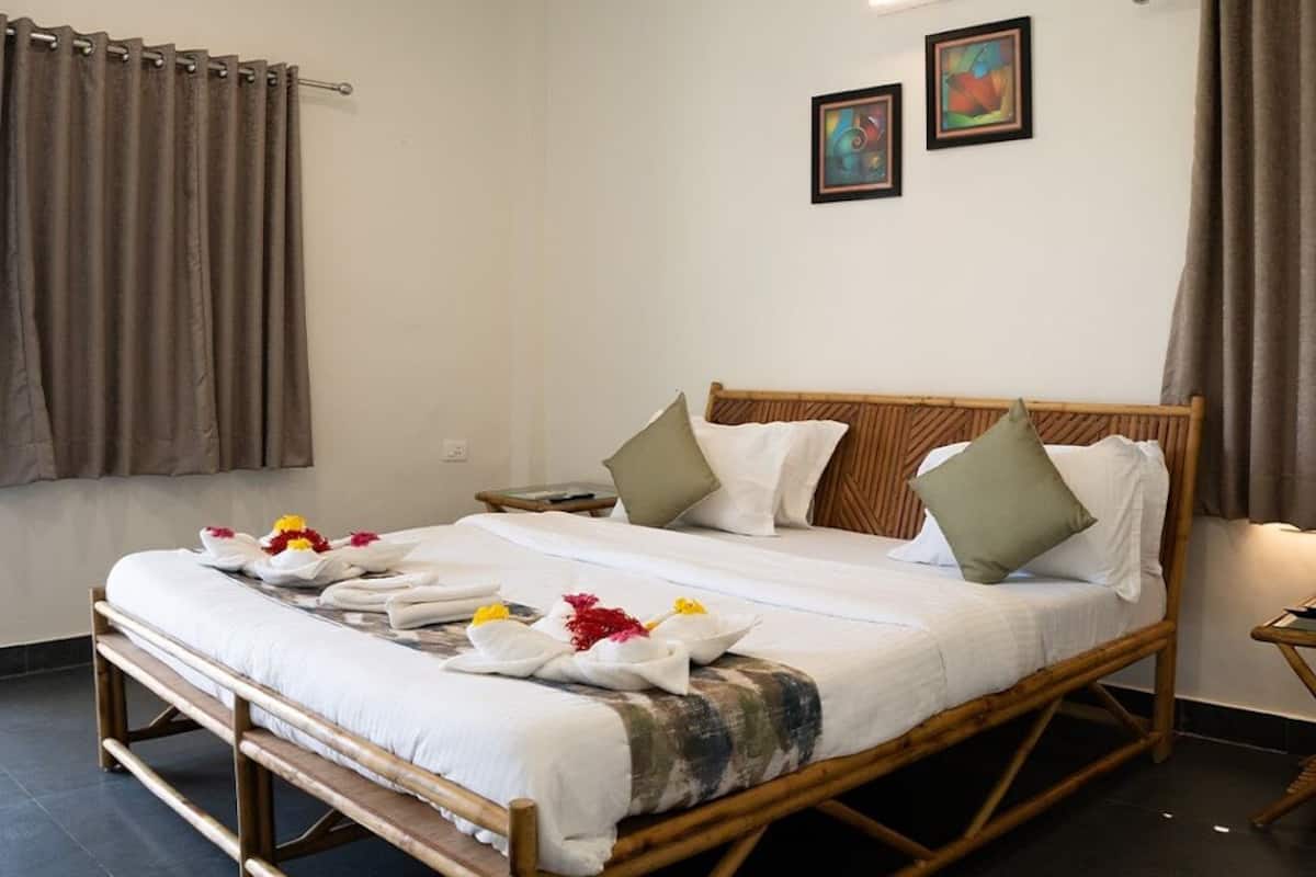 A neatly made bed with a wooden frame, white bedding, and decorative pillows. There are two framed artworks on the wall above the bed.