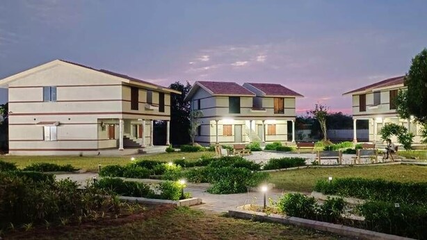 Un moderno complejo residencial con varias casas de dos pisos, jardines bien cuidados y una tranquila atmósfera vespertina.