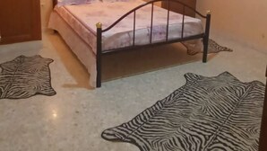 Quarto com cama, paredes de madeira e tapete com padrão de zebra.