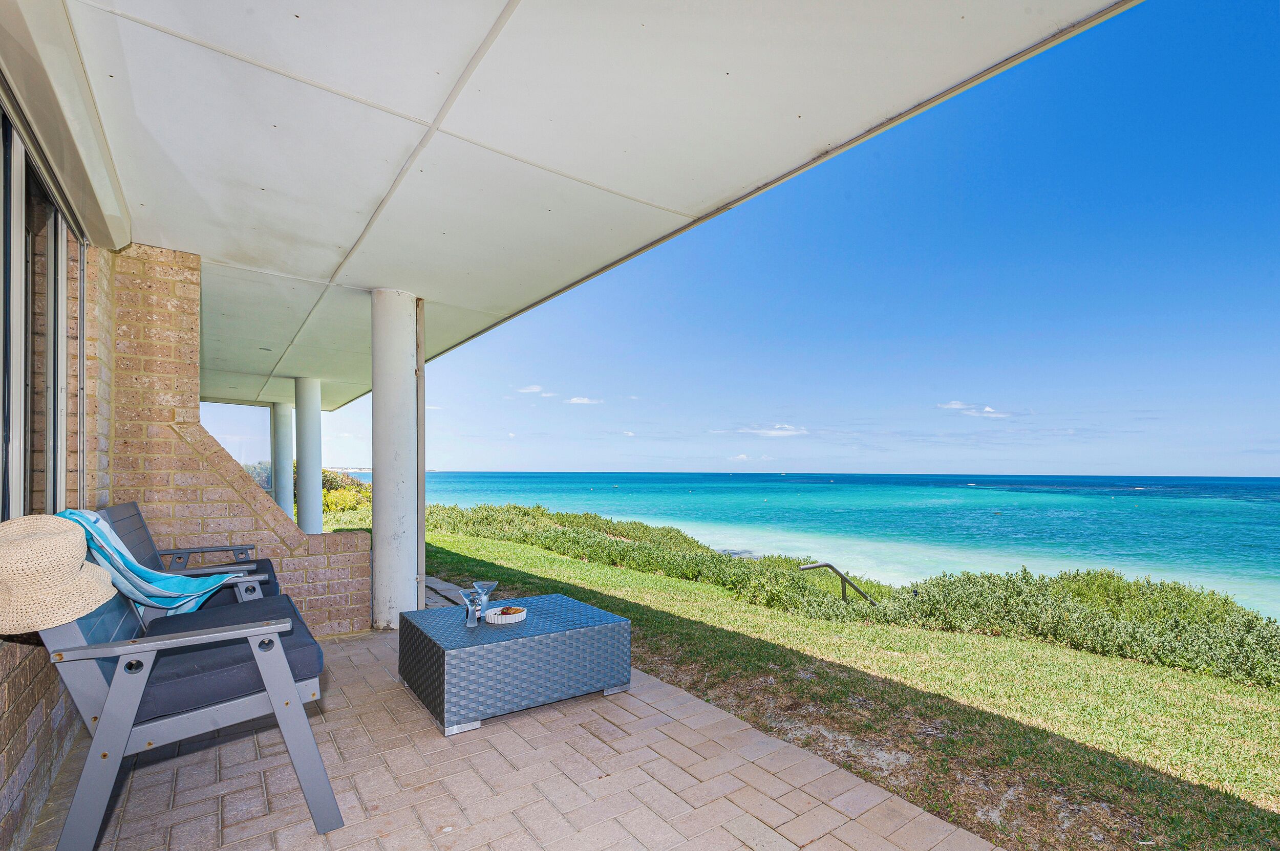 A covered outdoor seating area with a view of the ocean.