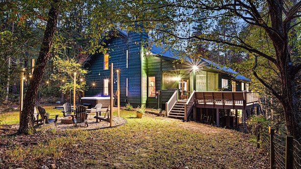 A rustic cabin with a deck, outdoor seating, and a fire pit.