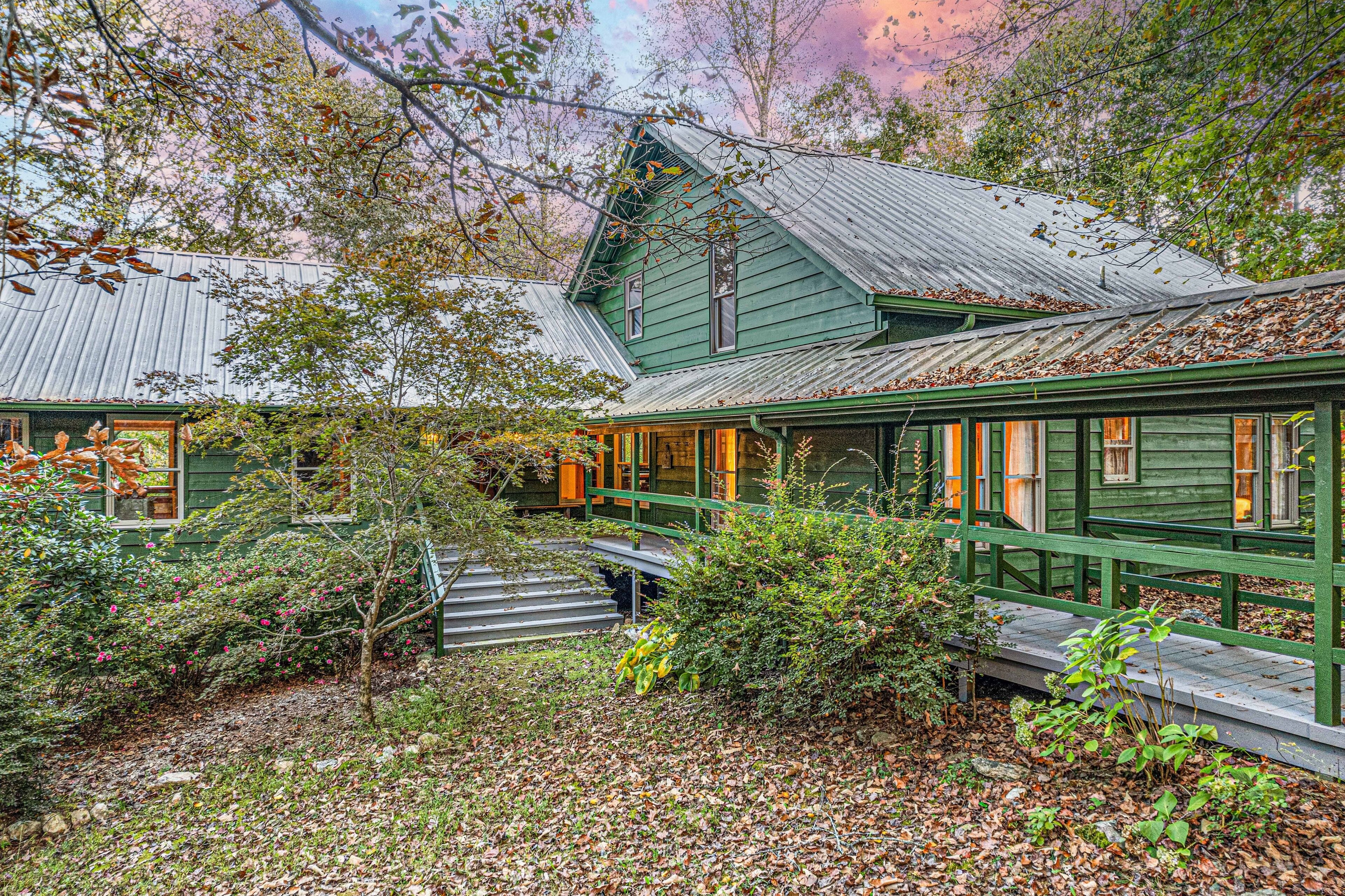 A rustic cabin with a wooden deck and a staircase leading to the entrance.