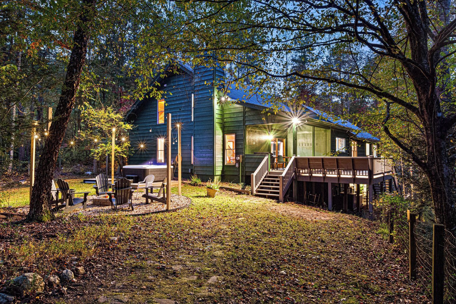 A rustic cabin with a deck, outdoor seating, and a hot tub.