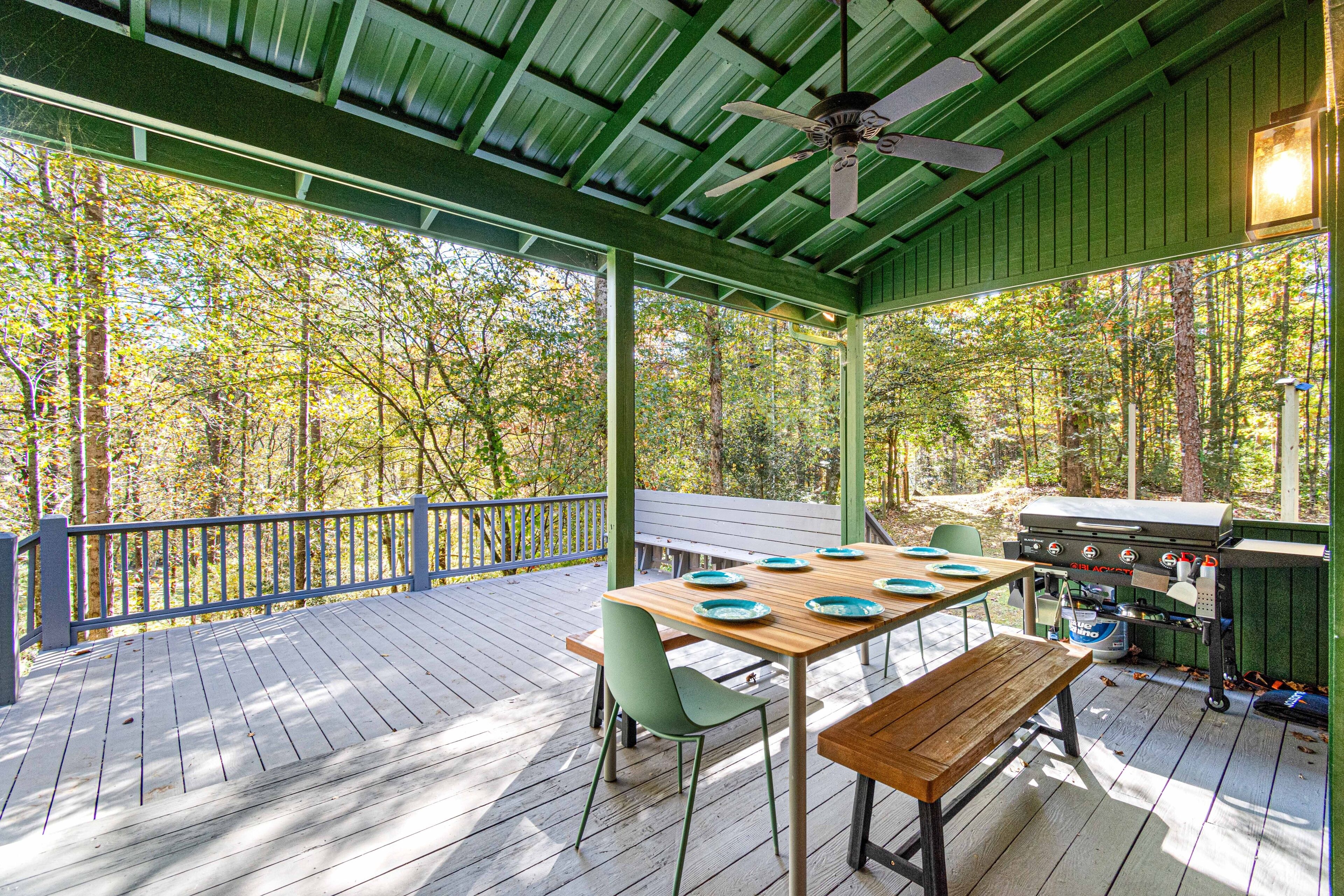 An outdoor deck with a wooden table, chairs, and a grill.