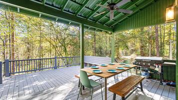 An outdoor deck with a wooden table, chairs, and a grill.