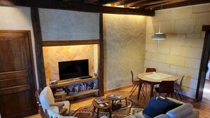A cozy living room with a fireplace, a television, a dining table, and comfortable seating. - Le Plessis-Lepage - "Le Gite" **** Calm-Space-Green at Azay-Le-Rideau (Azay-le-Rideau)