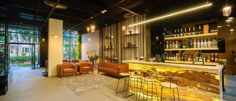A modern bar area with a marble countertop, bar stools, and a variety of liquor bottles.