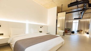 Una habitación de hotel moderna con una cama grande, una mesita de noche, un espejo y vistas a un comedor.