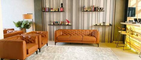 Ein modernes Wohnzimmer mit braunen Sofas, einem Couchtisch und einer gestreiften Wand mit Regalen.