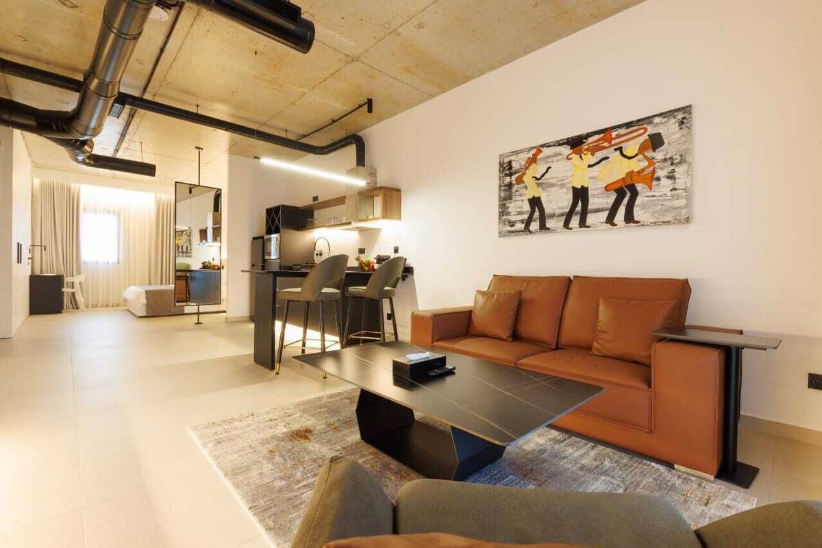 A modern living room with a brown sofa, a coffee table, and a painting on the wall.