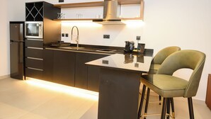 Una cocina moderna con horno empotrado, electrodomésticos de acero inoxidable, una isla central con taburetes de bar y un diseño elegante.