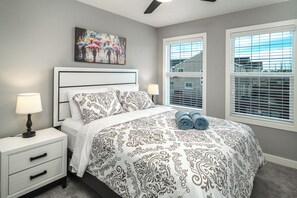 A bedroom with a bed, nightstands, a ceiling fan, and a painting on the wall. - Large new family home near Airport and mall!  I AC I Garage I Sleep 16+ (Calgary)