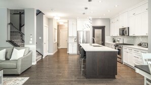 A modern kitchen with a central island, stainless steel appliances, and a staircase leading to an upper level.