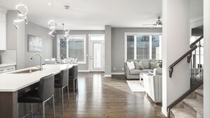 A modern kitchen with a central island, bar stools, and pendant lighting.
