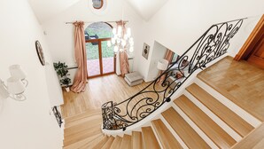 A modern staircase with a black metal railing, wooden steps, and a view of a garden through a glass door. - Lumina amazing house in Warsaw (Warsaw)