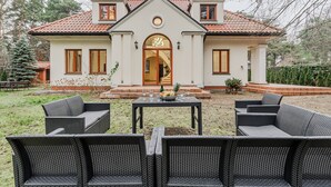 A house with a front porch, a dining table set with glasses and a bowl, and wicker furniture. - Lumina amazing house in Warsaw (Warsaw)