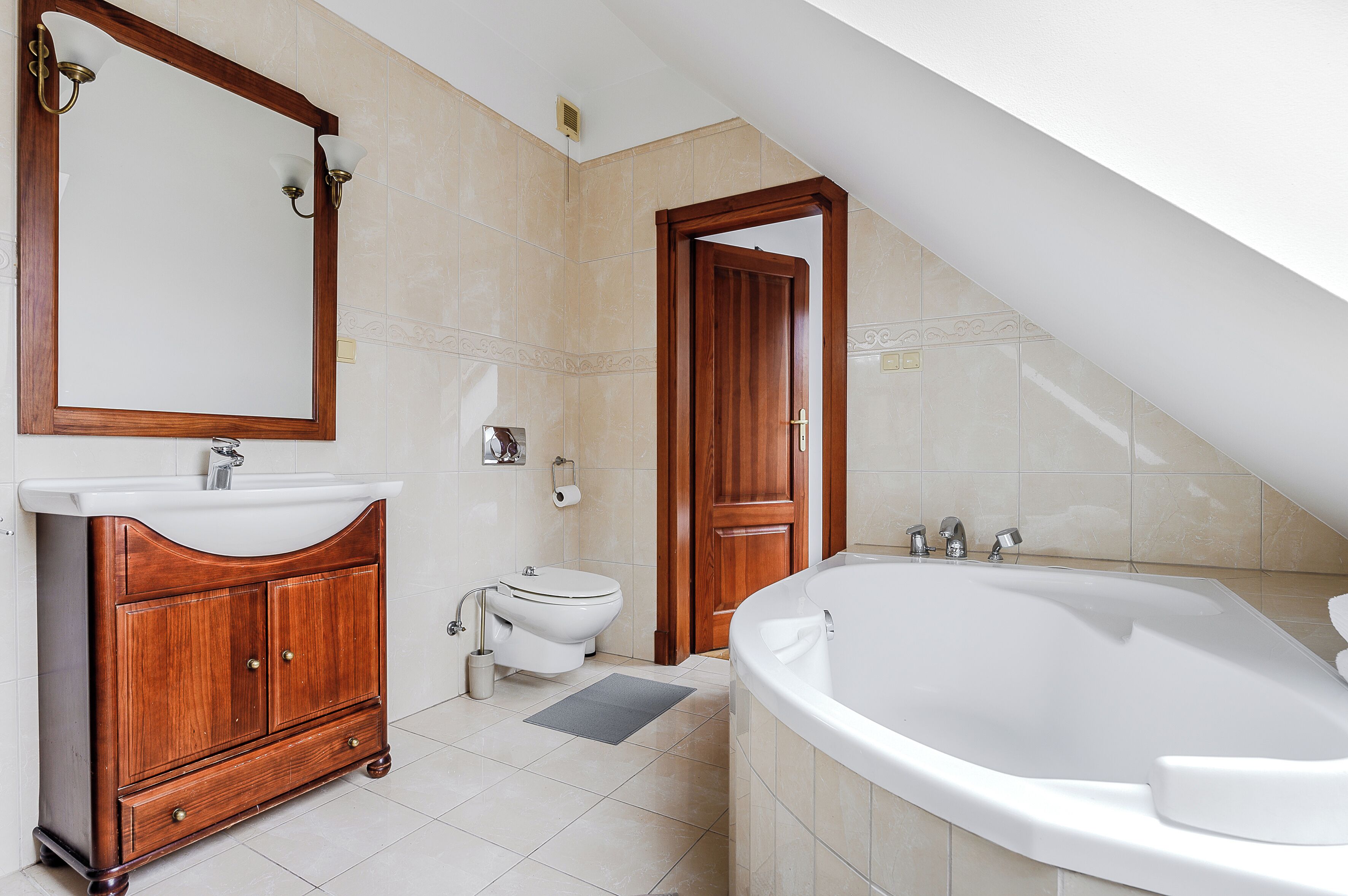 Une salle de bain avec un meuble-lavabo en bois, un lavabo blanc, des toilettes et une baignoire sur pieds.