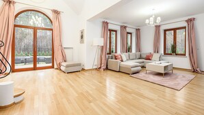 A spacious living room with a wooden floor, a sofa set, a coffee table, and large windows with curtains. - Lumina amazing house in Warsaw (Warsaw)