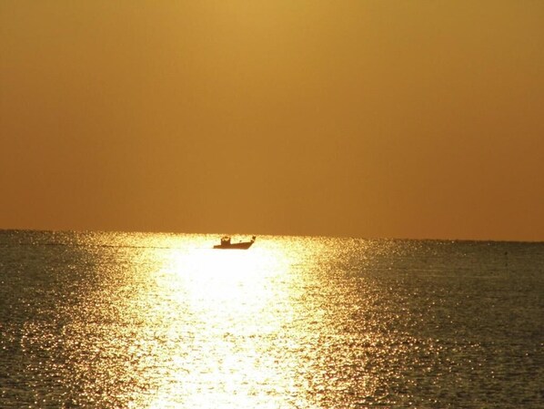 A boat on a calm sea during sunset.