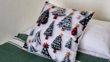 A pillow with a Christmas tree pattern on a bed with a green cover.