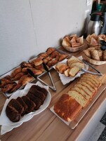 Una mesa de buffet con diversas opciones de panadería, incluyendo cruasanes, pan y pasteles.