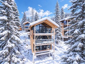 A modern wooden cabin with multiple levels, surrounded by snow-covered trees. - Superior Chalet # 25 with Sauna (Turrach)