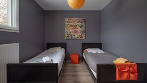 Una habitación con dos camas, un radiador, una ventana y un cartel llamativo en la pared.