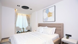 A modern hotel room with a large bed, a bedside table, a chair, and a small table with a plant. - Luxury 1-bedroom apartment in Diamond in the City in Cantonments  (Accra)