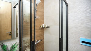 A modern shower with a glass door, wooden wall paneling, and a shelf with toiletries. - Luxury 1-bedroom apartment in Diamond in the City in Cantonments  (Accra)