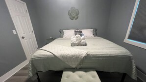 A bedroom with a bed, a bench, a nightstand, and a wall decoration. - Spacious 4-bedroom house in Columbus with privacy fence situated in the county! (Columbus)