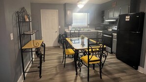 A compact kitchen with a dining table and chairs, a refrigerator, and a window with blinds. - Spacious 4-bedroom house in Columbus with privacy fence situated in the county! (Columbus)