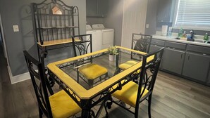A dining area with a glass-top table and yellow cushioned chairs, a ceiling fan, and a window with blinds. - Spacious 4-bedroom house in Columbus with privacy fence situated in the county! (Columbus)