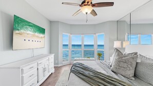 A bedroom with a large window offering a view of the ocean, a ceiling fan, a bed with a view, and a white dresser. - Carnoustie Sandestin Bayfront Condo Golf Cart (Miramar Beach)