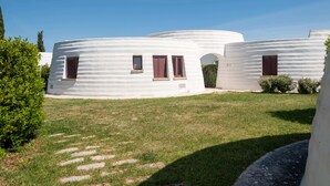 A cluster of white, dome-shaped buildings with small windows and shutters, surrounded by a grassy area with a clear sky. - Hotiday Gallipoli Masseria (Tuglie)