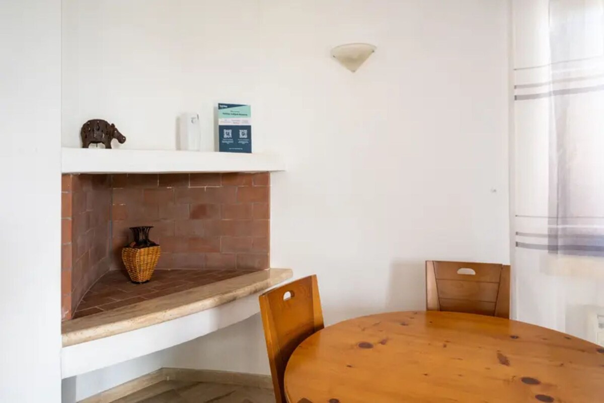 Un coin repas avec une cheminée en briques, une table ronde en bois et deux chaises.