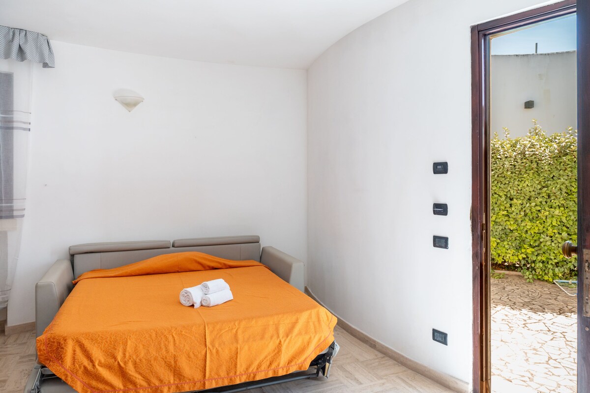 Une pièce comprenant un lit, une porte donnant sur un espace extérieur et un luminaire fixé au mur.