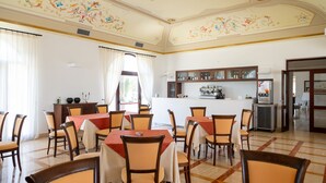 A dining area with tables and chairs, a kitchen area with cabinets and appliances, and a decorative ceiling. - Hotiday Gallipoli Masseria (Tuglie)