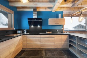 Una cocina moderna con armarios de madera, una estufa negra y una pared azul decorativa.