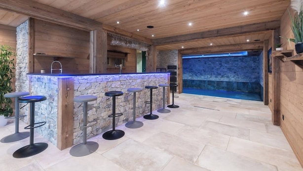 A bar area with a stone counter and bar stools. - Chalet Elixir - 14 guests - Pool & Sauna, Gérardmer (Gérardmer)