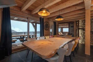 A spacious dining area with a large wooden table, multiple chairs, and pendant lighting.