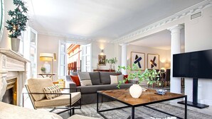 A modern living room with a sofa, armchairs, a coffee table, and a TV. - Genteel Home San Fernando (Seville)