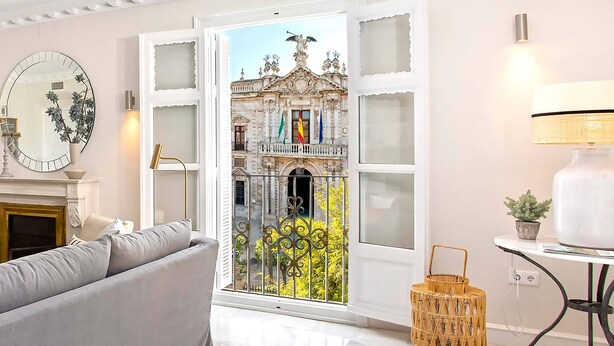 A living room with a large window, a sofa, a mirror, and a lamp. - Genteel Home San Fernando (Seville)