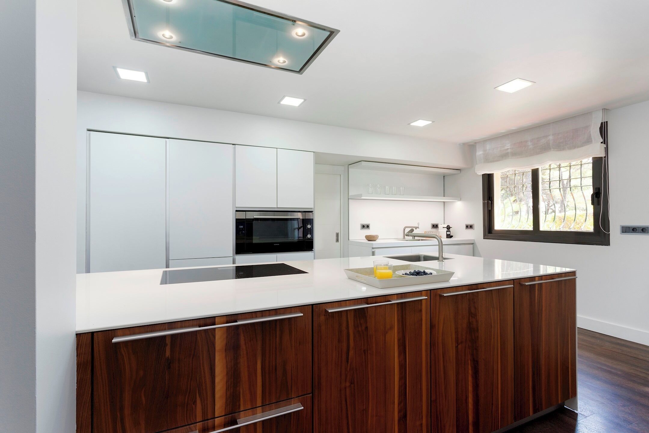 A modern kitchen with white cabinetry, a central island, and a microwave.