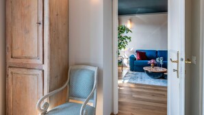 A room with a wooden door, a blue sofa, and a coffee table with decorative items. - Genteel Home Piazza Pitti (Florence)
