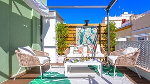 A patio with wicker furniture, a white table, and a decorative wall.