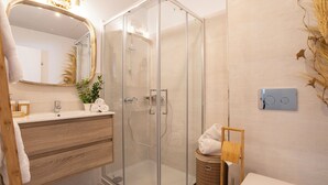 A modern bathroom with a glass-enclosed shower, wooden vanity, and a large mirror.